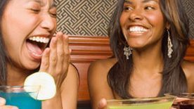 2 young women laughing over cocktails