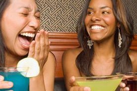 2 young women laughing over cocktails