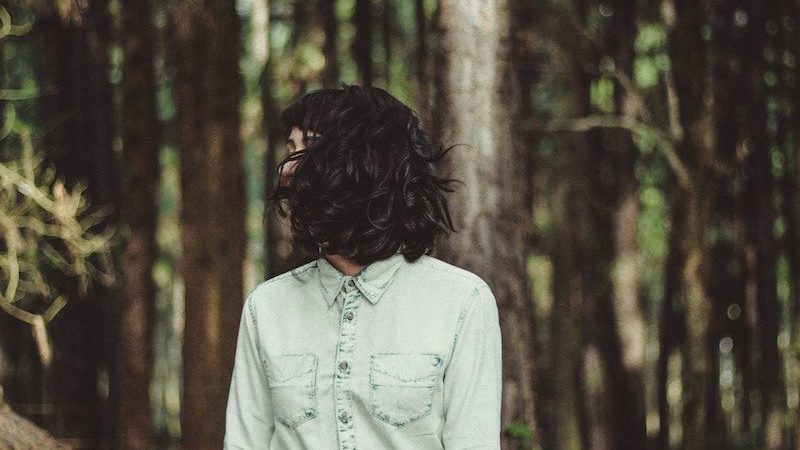 Young woman standing in forest with hair covering her face