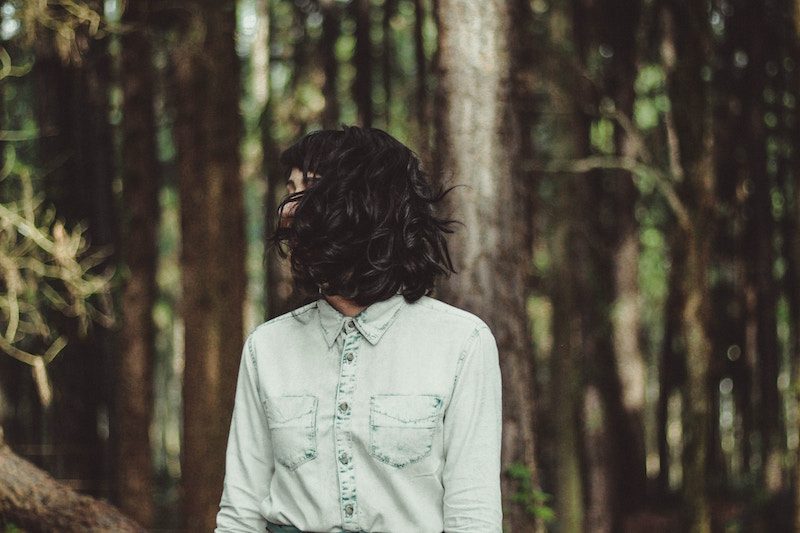 Young woman standing in forest with hair covering her face